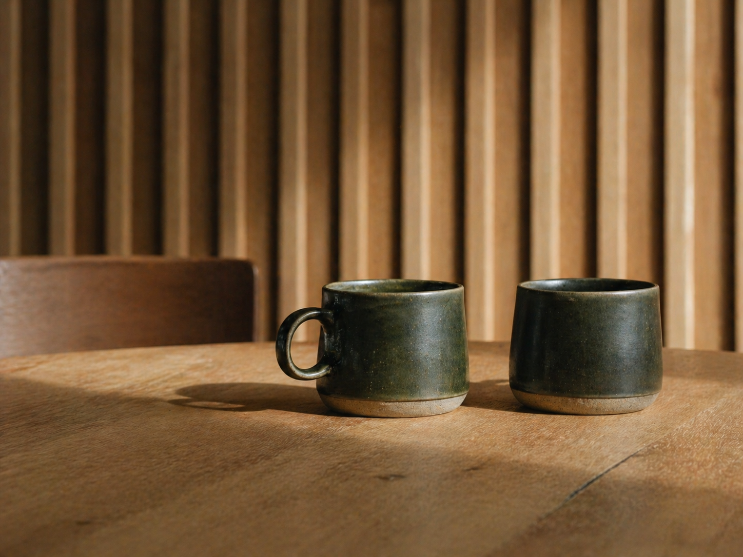 Två keramikmuggar på ett bord av massivt trä